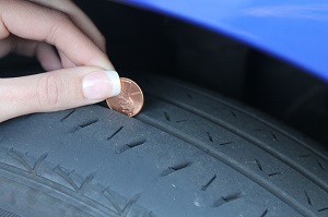 A person is checking tire grips with a coin