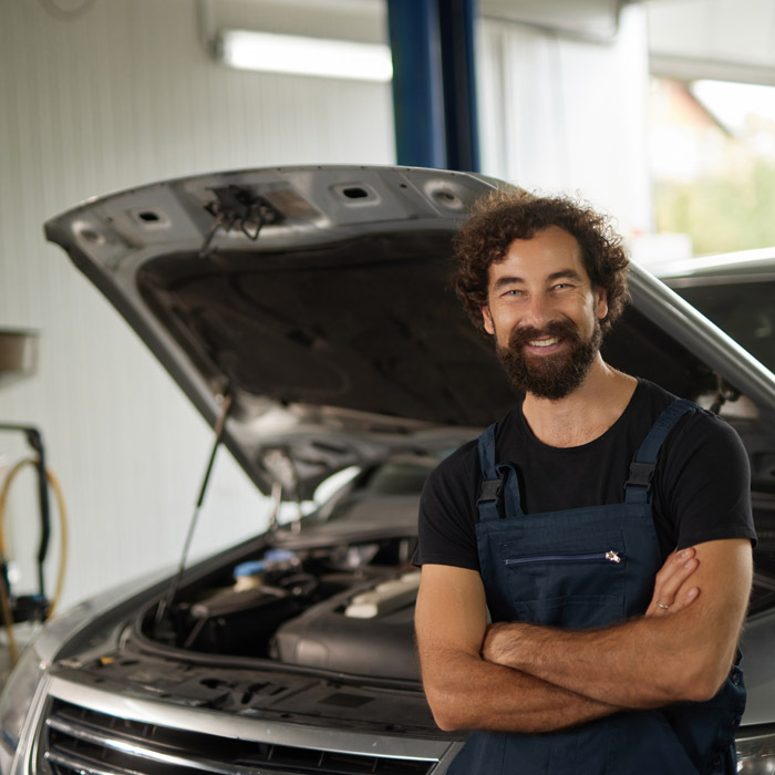 mechanic leaning on car with hood open